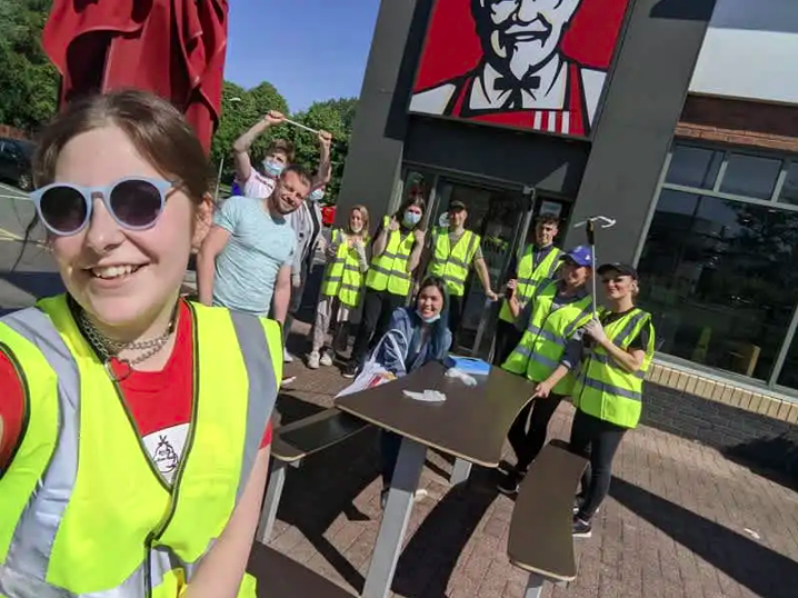 KFC employees in hi-vis vests cleaning up litter
