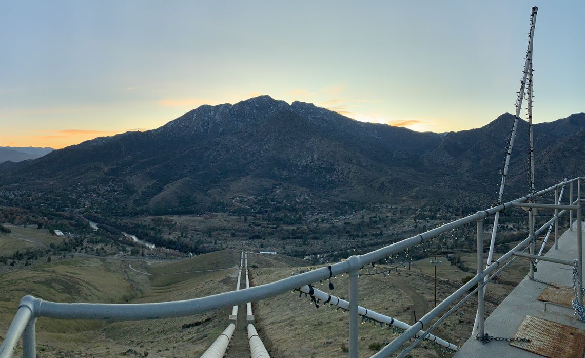 Panoramic view of the valley from a tall building with a safety rail. A road leading down the hill.