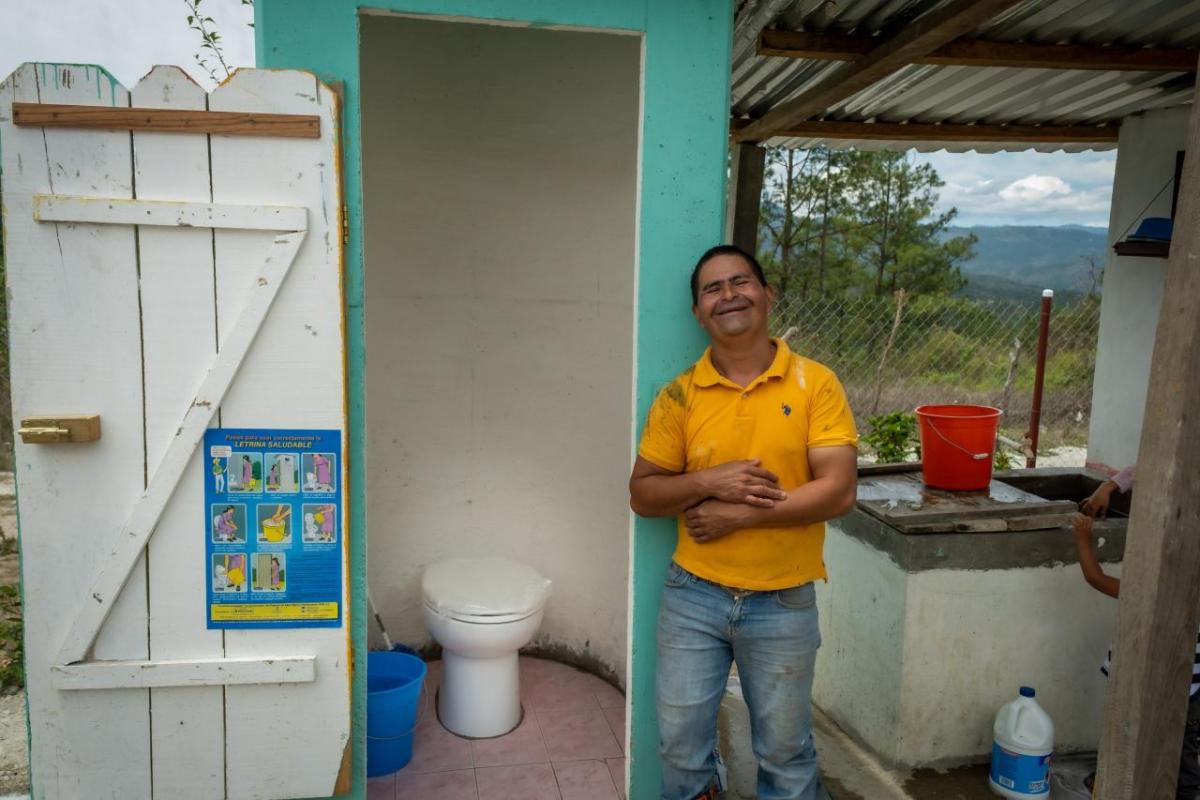 Person smiling next to a new toilet