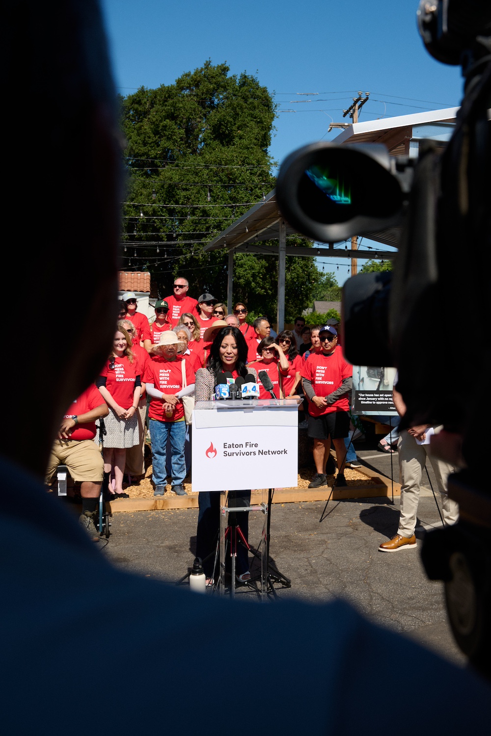A person speaks to the media, surrounded by survivors of the LA wildfires, at an event in California.