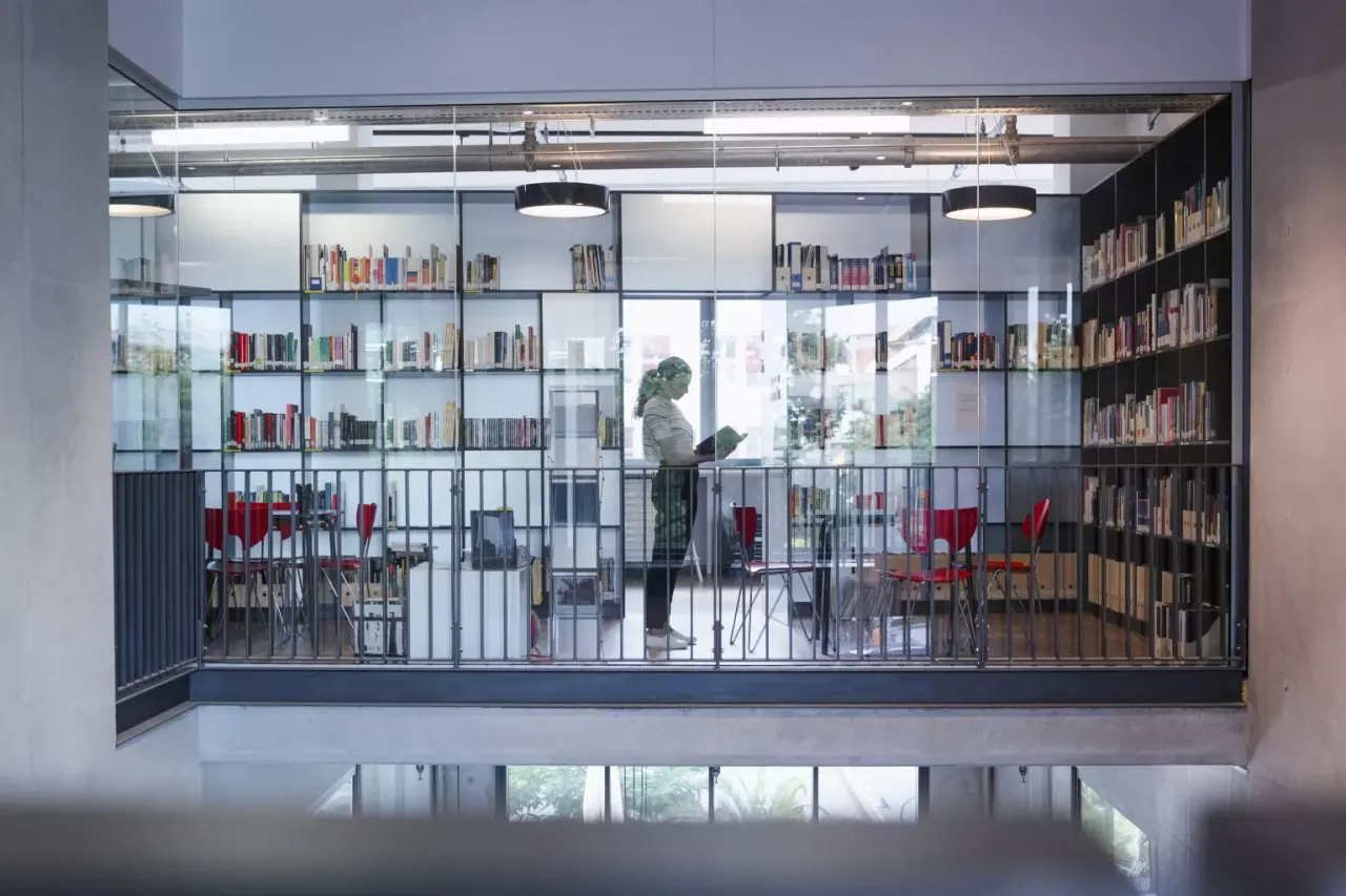 A person behind a glass wall of a library.