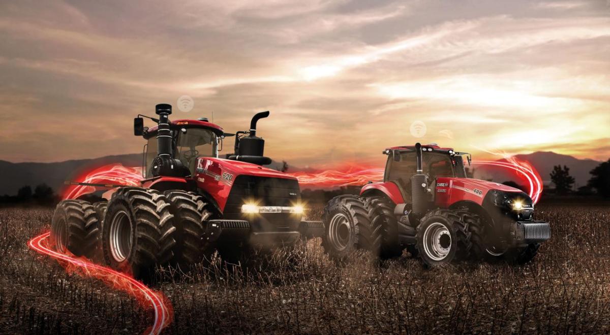 Two red tractors in a farm field, setting sun in the distance and red digital lights behind them.