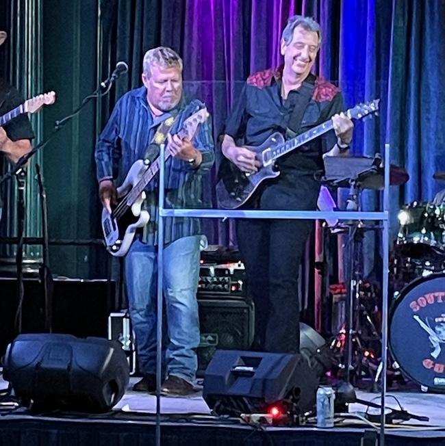 HARMAN employees playing electric guitars on stage.