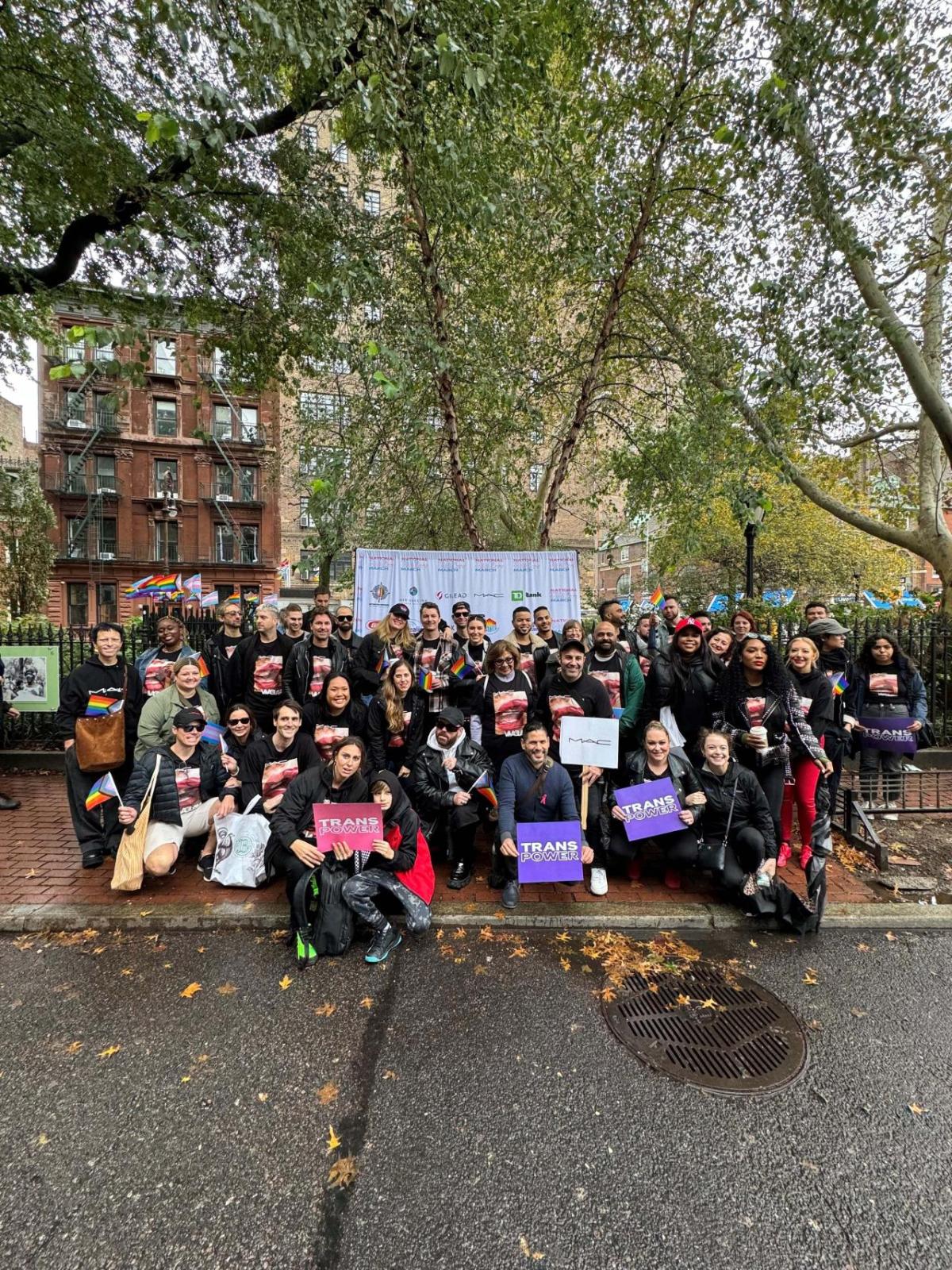 A large group posed on a sidewalk holding signs for Trans Day of Visibility.