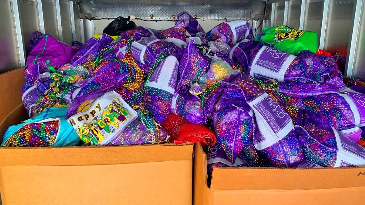 Dozens of bags of mardi gras beads with recycle image and "Happy Mardi Gras" printed on them.