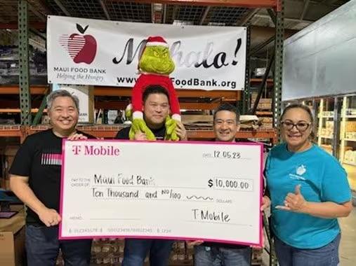 A small group of people holding a donation cheque for Maui Food Bank