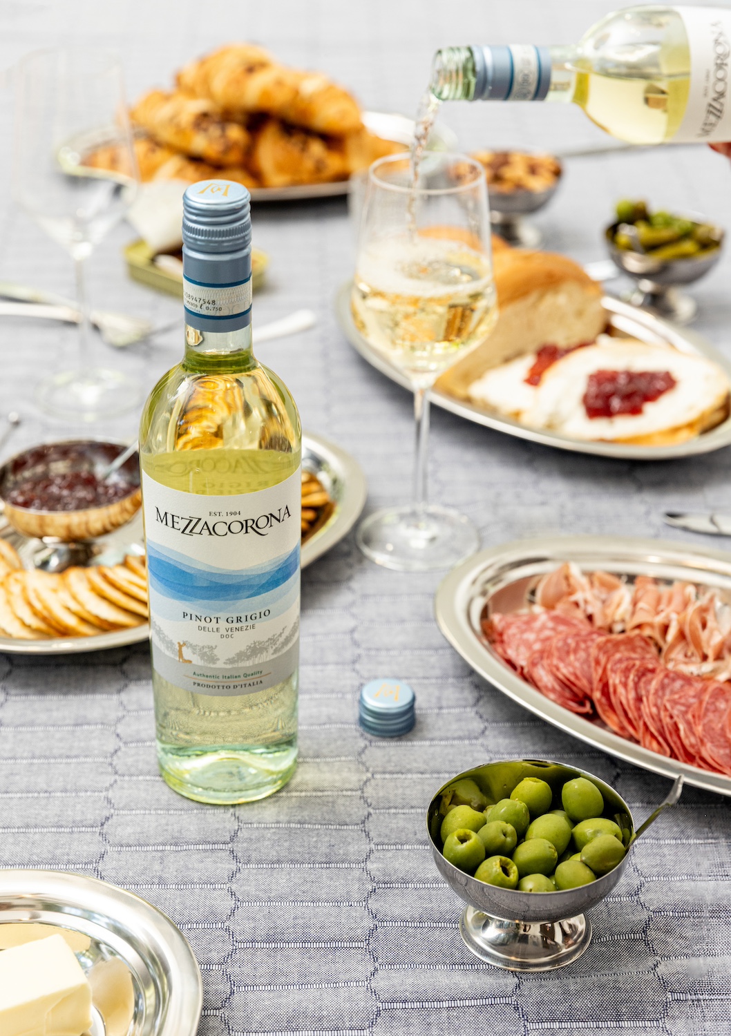 A Mezzacorona wine bottle on a table surrounded by hors d'oeuvres — sustainable wine
