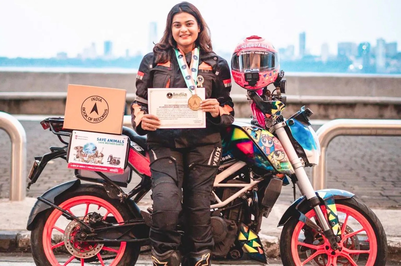 Vishakha Fulsunge standing in front of her motorcycle, wearing a medal and holding a certificate from the India Book of Records