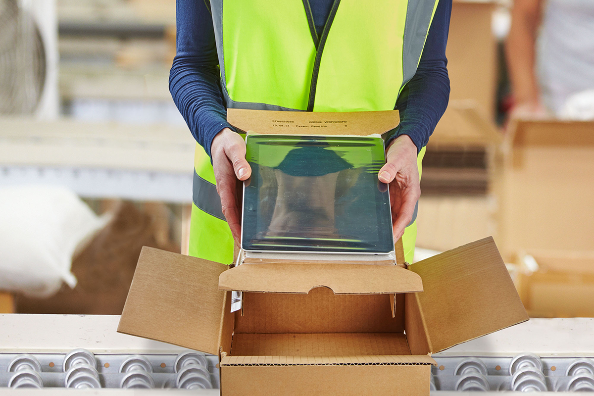 Item in a box held by a person in yellow vest