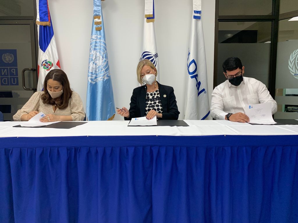 three people signing papers at table