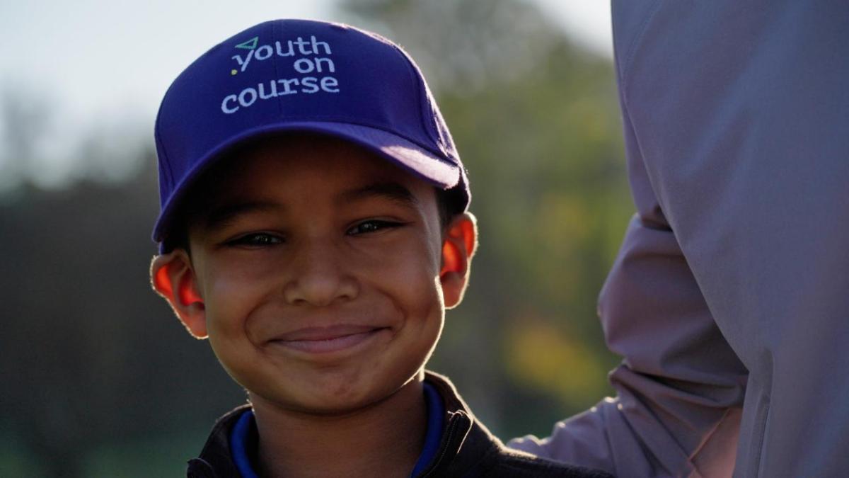 Child, smiling, shown wearing Youth on Course hat.