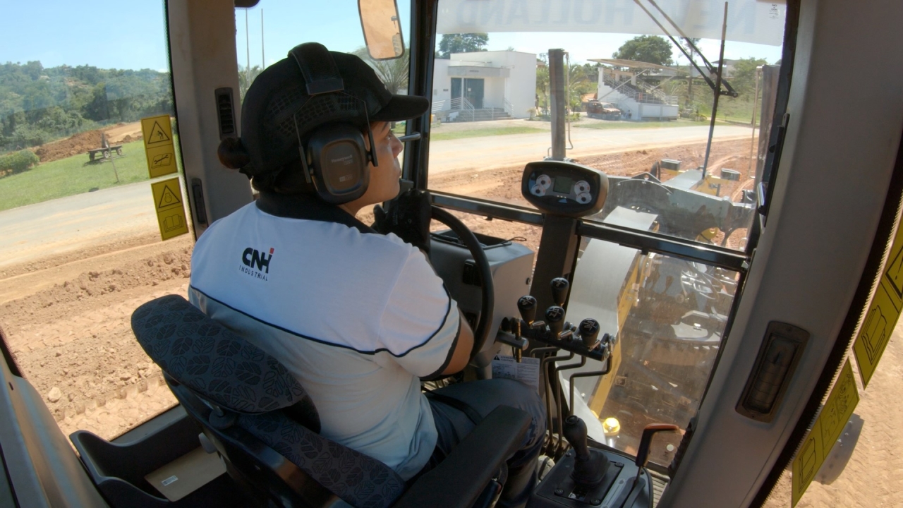 A woman learning to operate a New Holland Construction machine.