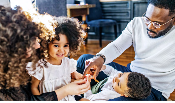 family of four seated on the floor of their home.