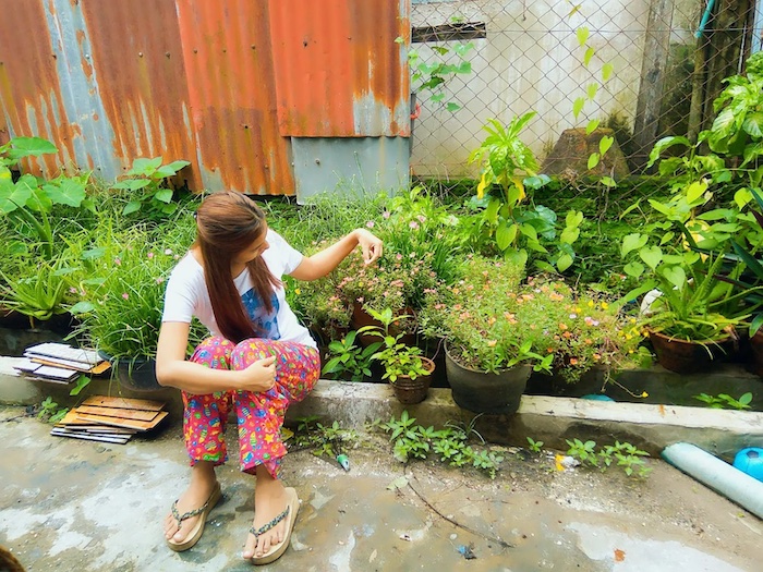 Woman tending to flowers and potted plants.