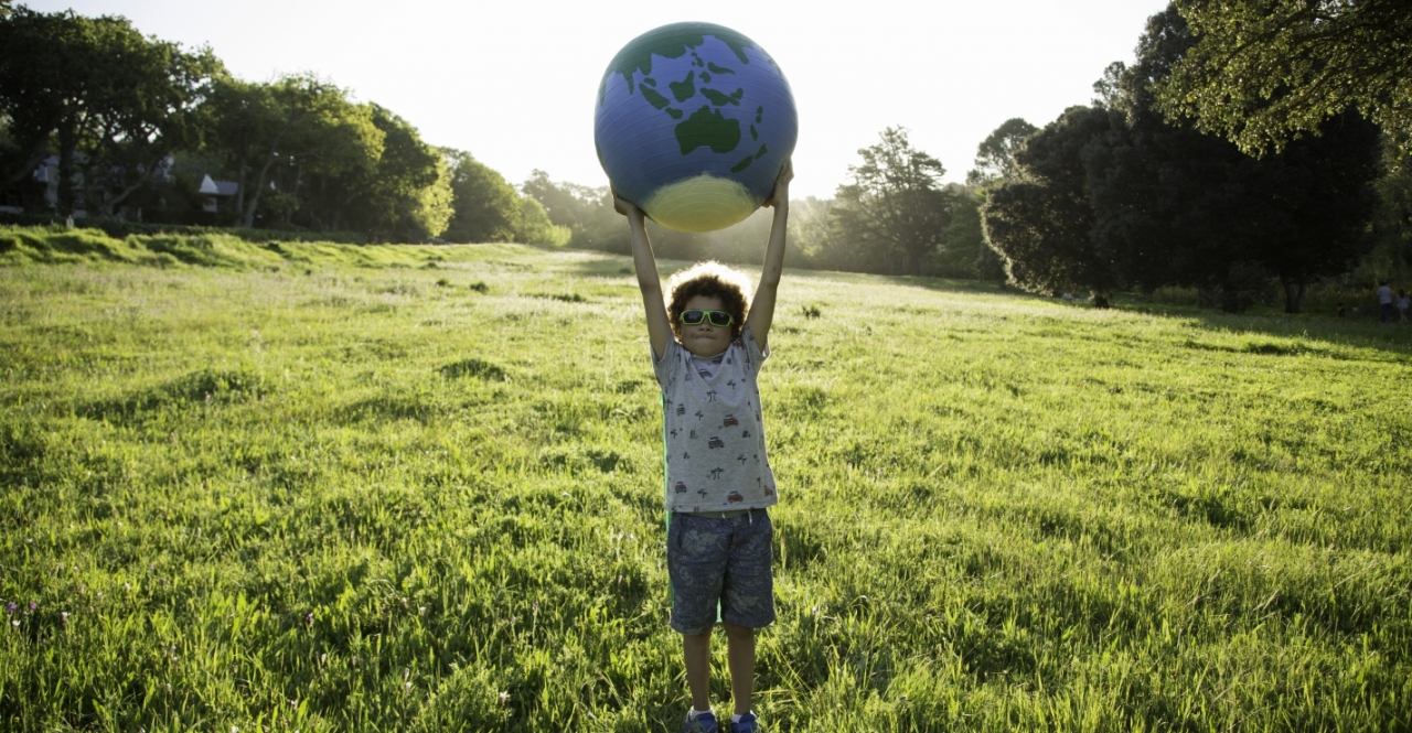 Child holding a globe above his head in a field