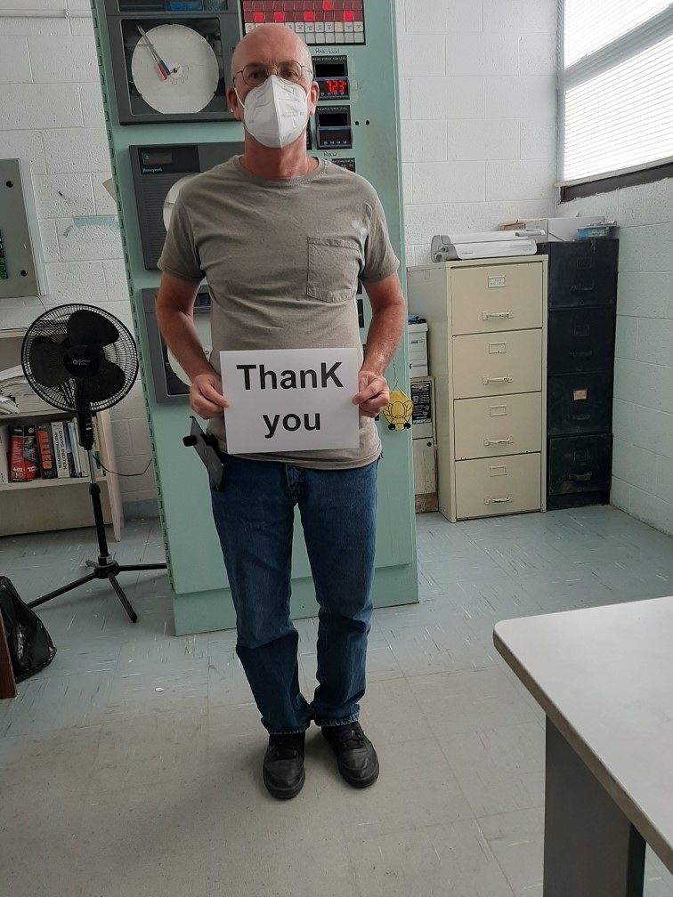 A man wearing a mask and holding a sign reading, "Thank You"