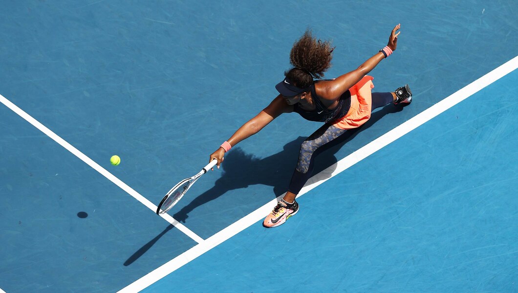 Image of Naomi Osaka playing tennis on bright blue court
