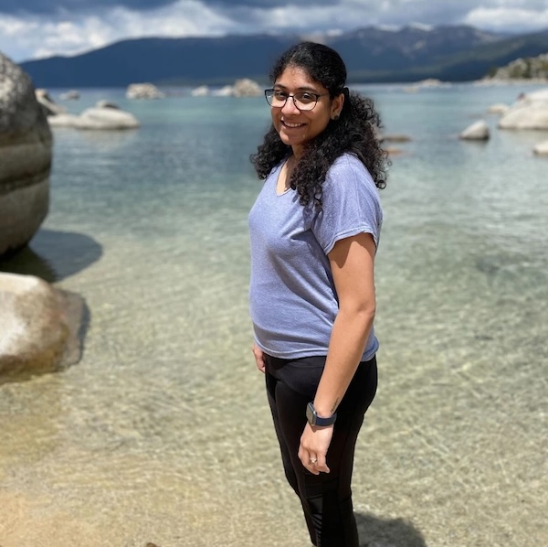 Sanjana standing at the edge of the water at a beach.