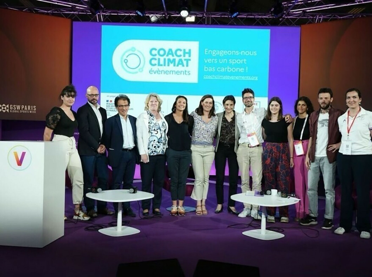 Group of stood together smiling in front of a screen at an event 