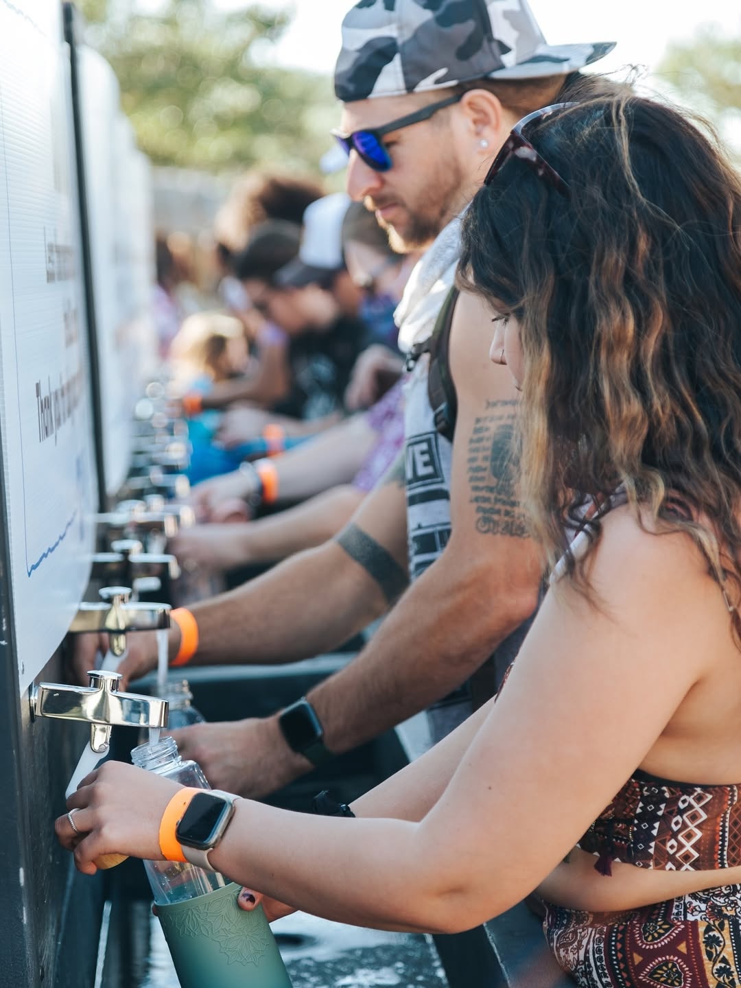 people use a water station at a music festival — sustainability at music festivals