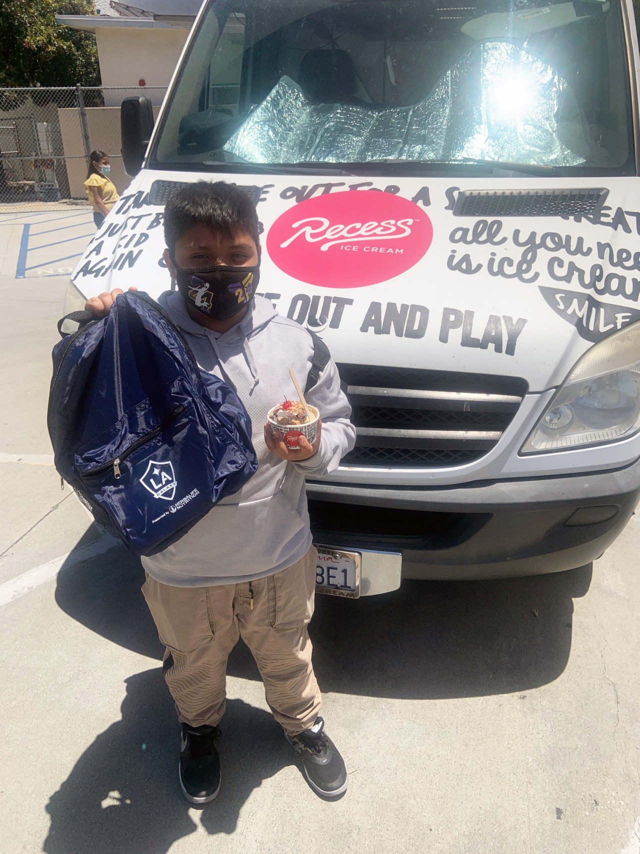 student holding backpack and ice cream