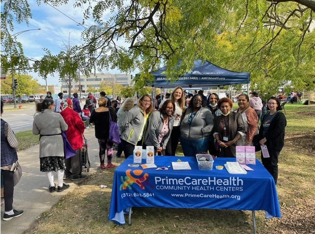 Group standing behind PrimeCare Health table in a park