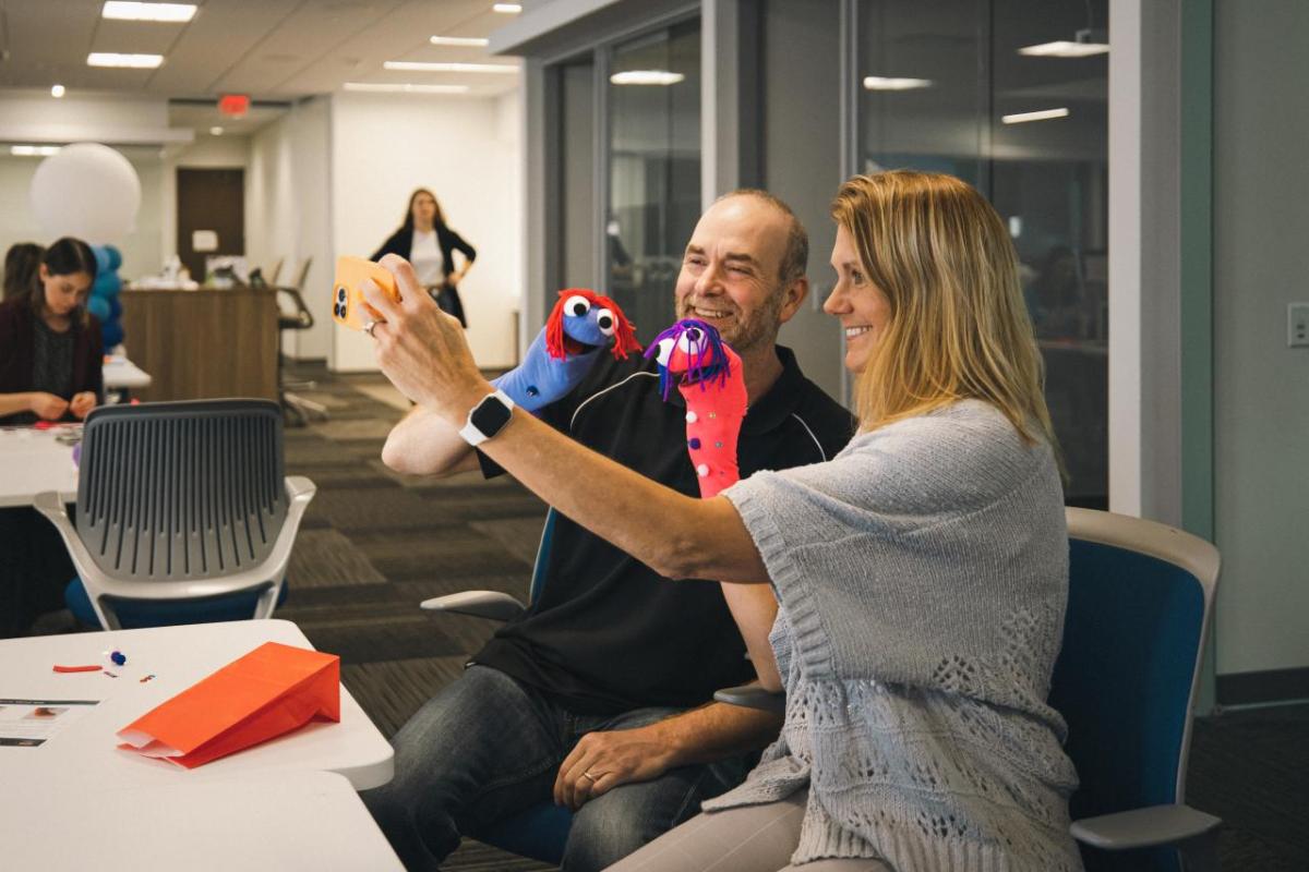 Woman and a man taking a selfie at a desk.
