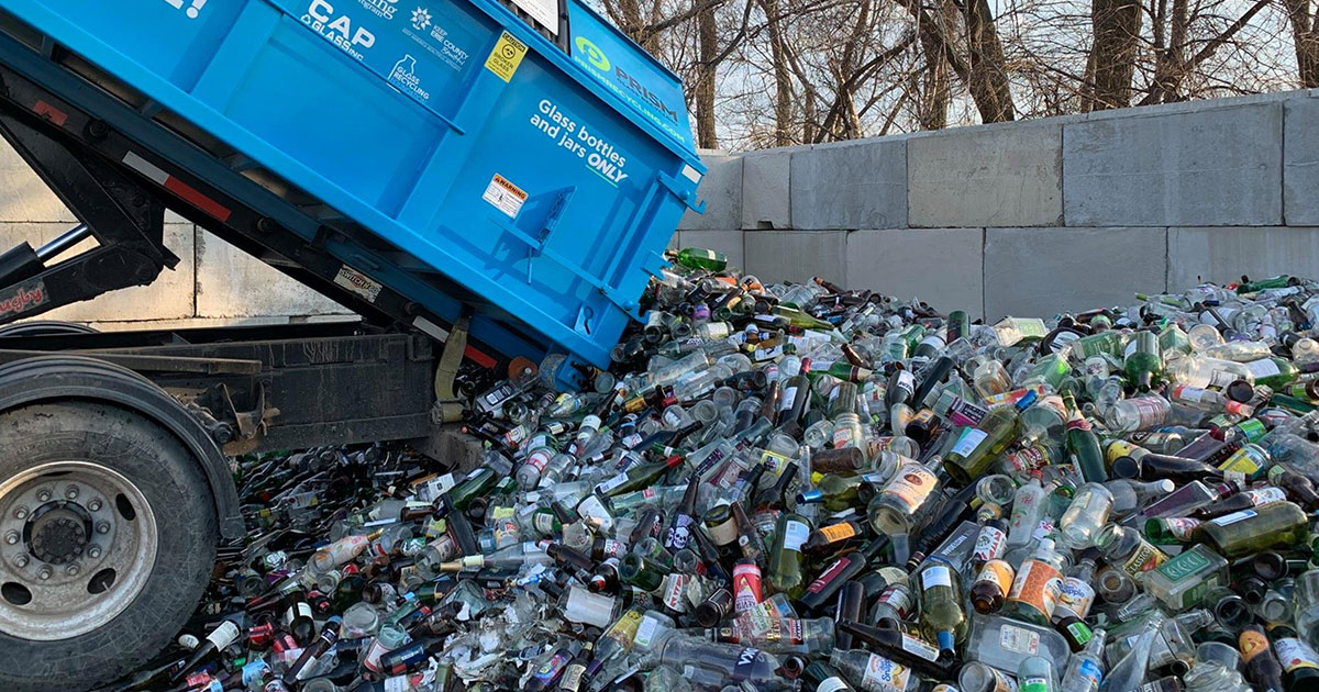 recycling truck dumping glass bottles into pile