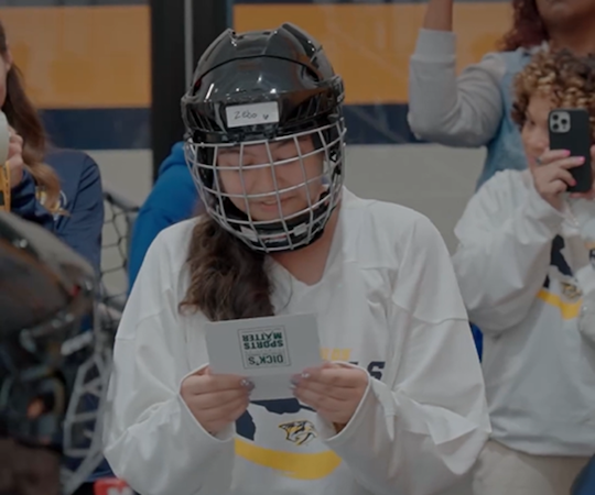 Play like a girl. Young girl shown in a hockey uniform reading a letter.