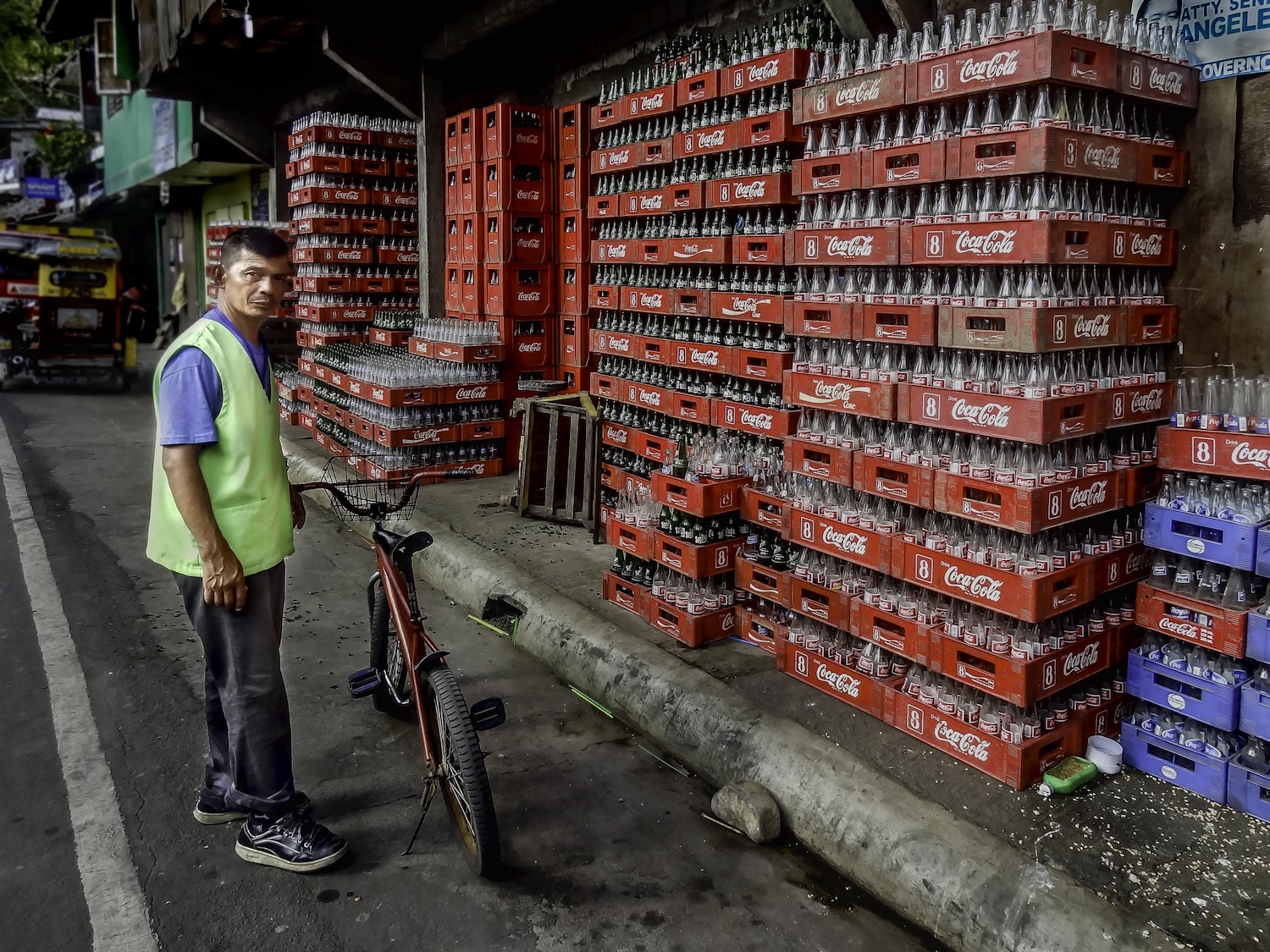 Refillable packaging - worker prepares to move empty refillable glass coca-cola bottles in the philippines