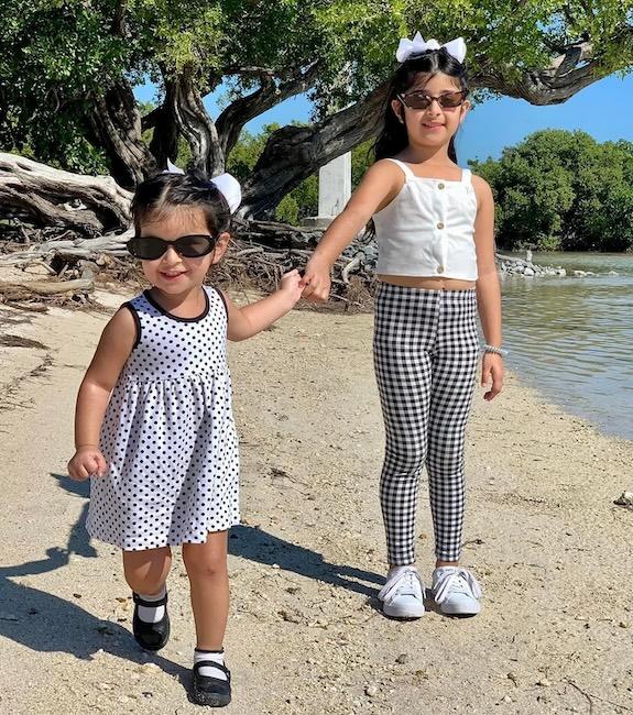 Richa Gandhi's two daughters shown near a pond holding hands.
