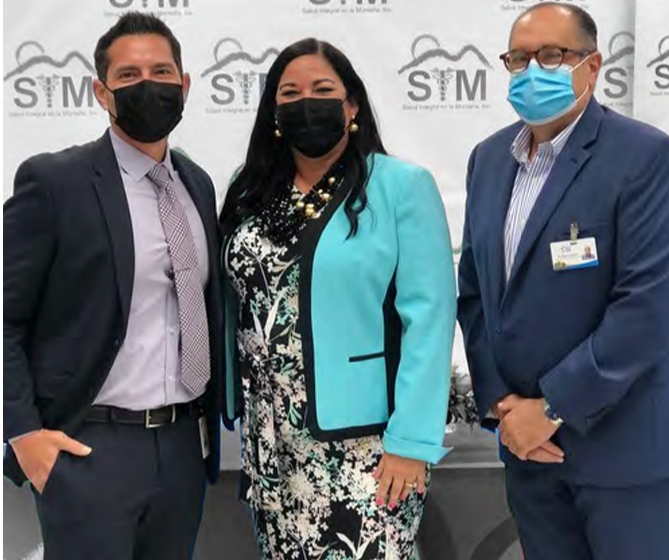 Three people wearing protective masks in front of a wall with SIM logos