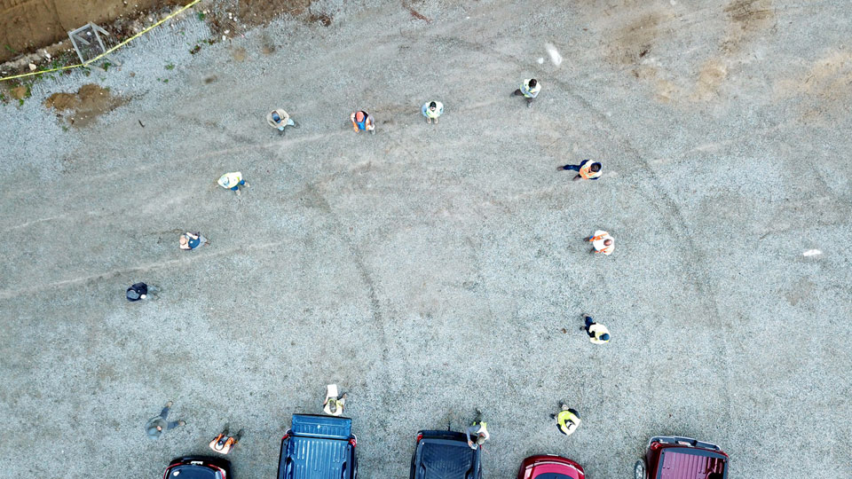 bird's eye view image of several people standing spaced apart in a parking lot