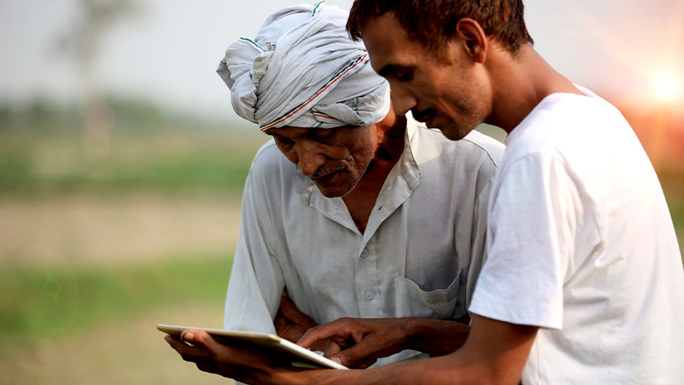 Two men looking at a tablet outside