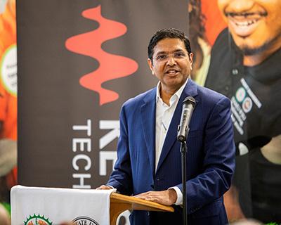 Satish Dhanasekaran standing at a podium with a microphone.