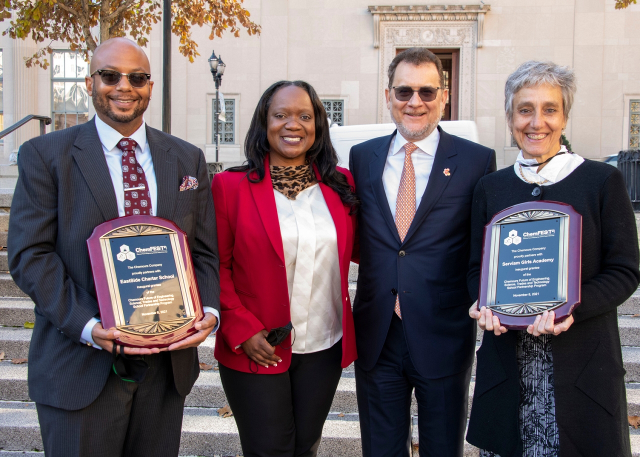 4 people standing together for a picture, 2 holding plaques