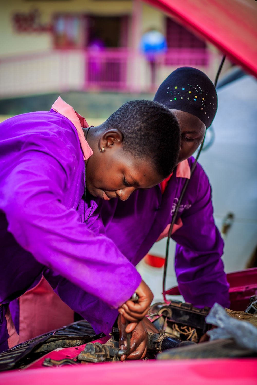 Smart Girls Uganda students working on a car. 