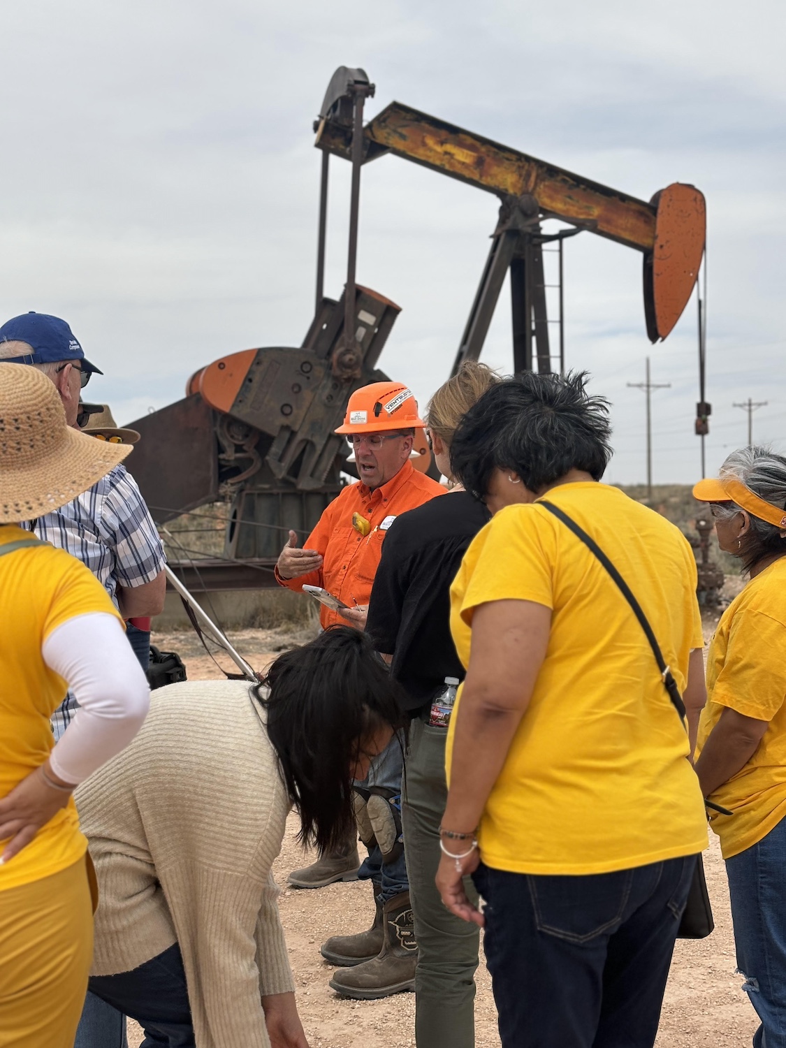 Somos members stand around an oil pump. 