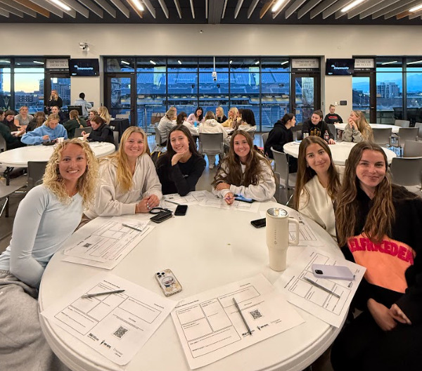 Student-athletes smile at the camera while siting together at an event held by the Student-Athlete Venture Studio.