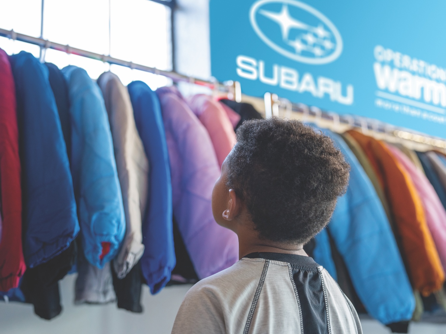 Subaru Coat Drive with Operation Warm - boy looks at coats
