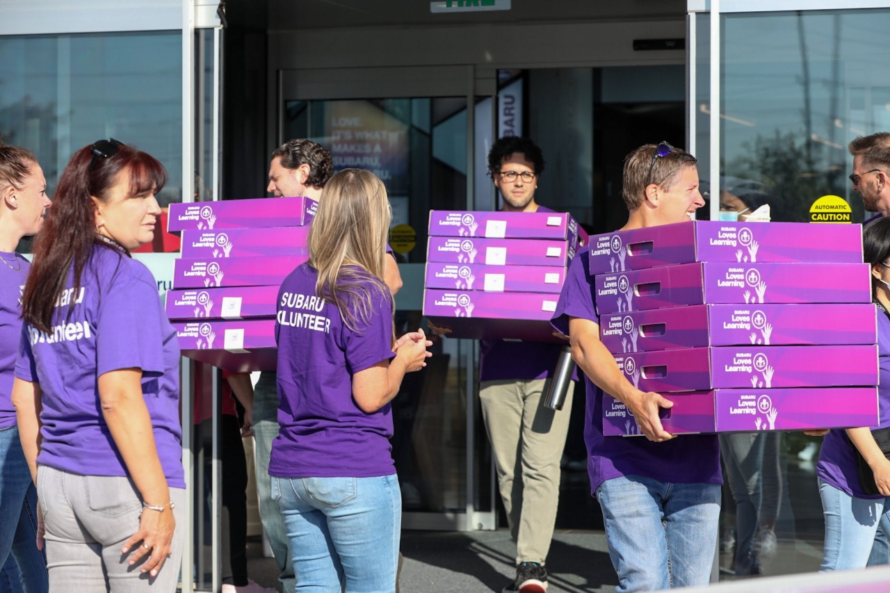 students help carry boxes into the school