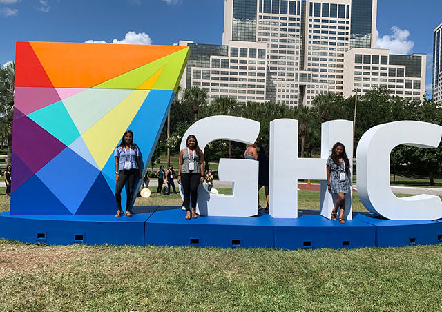 people standing in front of "GHC" statue