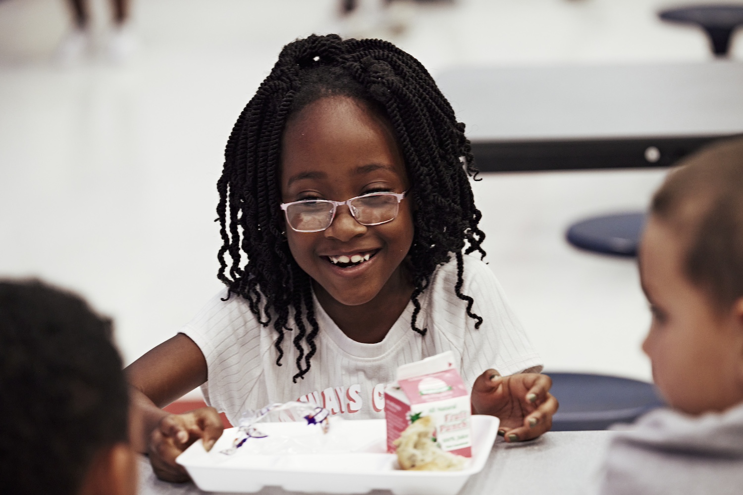 A young student smiling while eating a meal supplied by the summer meal program.