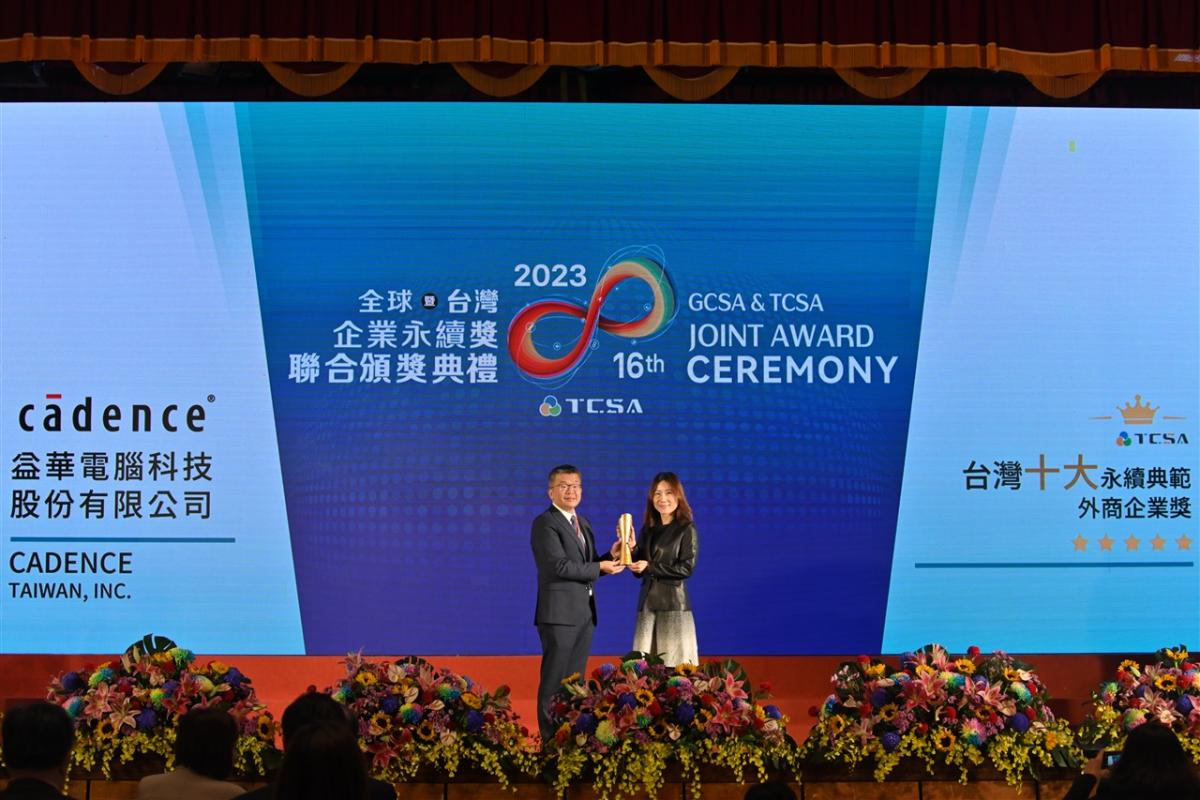two people holding an award on stage with a blue and white projection behind them