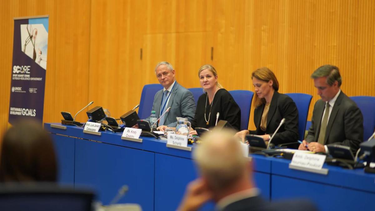 A panel of four at official desks.