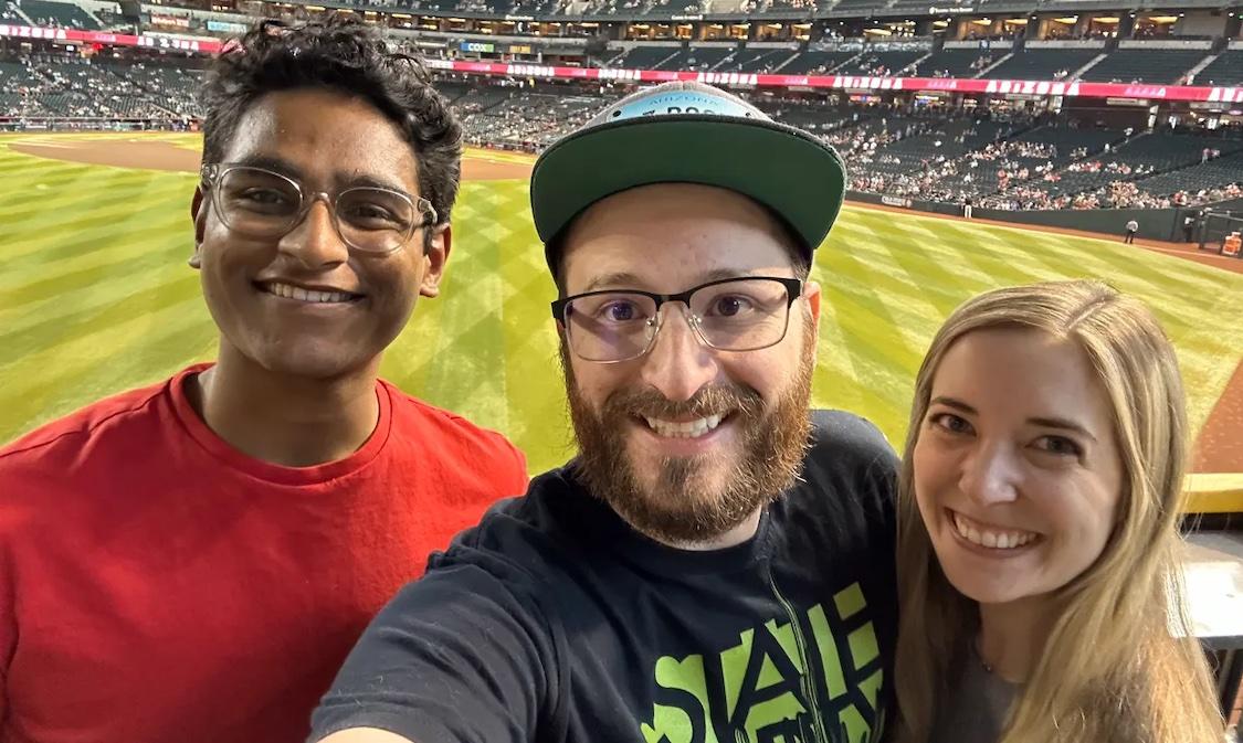 Tanishq and two friends at a baseball game.