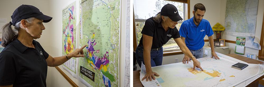 Terri in an office, pointing to a map on a wall, and looking at at map on a table with another person.