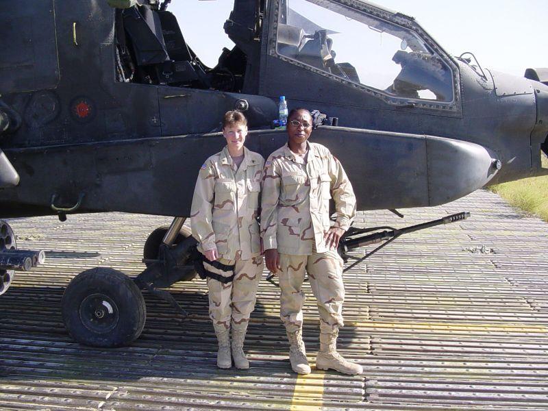 Tinisha Roberts in military uniform next to another person in front of a helicopter.