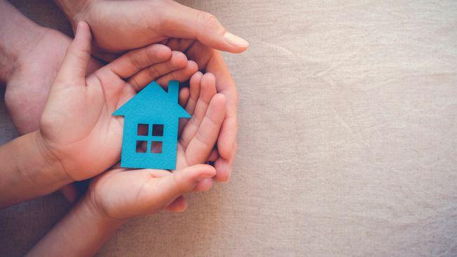 Someone holding a very small blue house in his hands