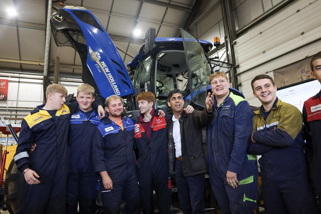 UK Prime Minister, Rishi Sunak, stood infront of a blue tractor with New Holland engineering apprentices 
